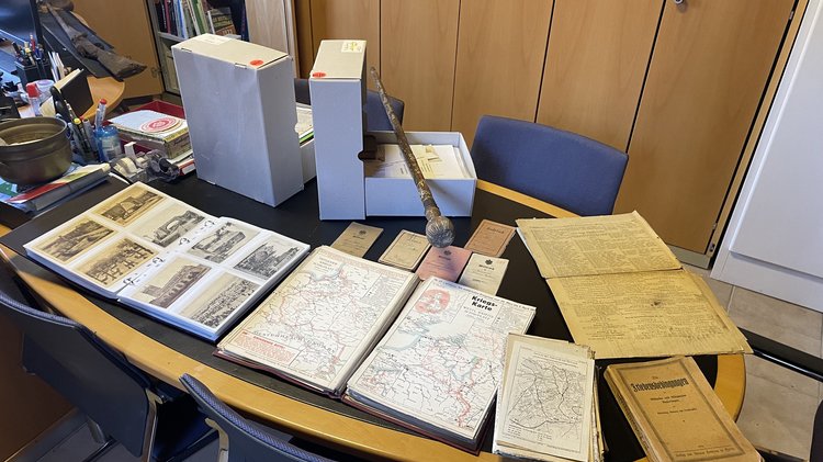 Ein Tisch in einem Büro, bedeckt mit Archivmaterialien